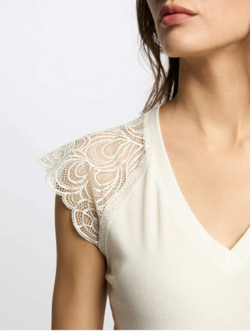 wit tshirt met kant mouw witte kanten top met vlinder mouwtje van de spring collectie Morgan de toi 1. **Kant**: Het gebruik van kant voegt een elegant en vrouwelijk element toe. Zorg ervoor dat de kwaliteit van het kant hoogwaardig is, zodat het zowel comfortabel als duurzaam is. 2. **Vlinder Kapmouwtje**: Dit geeft een speelse en tegelijkertijd verfijnde uitstraling. Het kan ook helpen om de schouders en armen mooi in balans te brengen. 3. **Strakke Pasvorm op de Schouders**: Dit creëert een nette, gestructureerde look die de schouders accentueert en een slanker silhouet bevordert. 4. **Speelse Ruimte vanaf het Middel**: Dit ideaal voor een comfortabele fit en geeft bewegingsvrijheid. Het kan ook zorgen voor een casual uitstraling zonder in te boeten op elegantie.