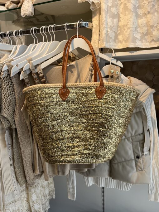 rieten strandtas boho goud 39.95 Super gave rieten strandtas met dichte rietrand en gouden pailletten. Onze Westmoodz collectie rieten strandtassen zijn handmade gevlochten tassen… de pailletten zijn er stuk voor stuk opgenaaid waardoor ze stevig vast zitten op het riet. De rieten strandtas is afgewerkt met extra lange leren hengsels, zodat deze makkelijk op de schouders kan worden gedragen. De hengsels zitten vast aan de tas met metalen spikes, waardoor het geen probleem is om lekker veel spullen/gewicht mee te nemen. Dat maakt de tas heel handig en leuk als shopper…maar helemaal geweldig voor een dagje on the beach! De strandtas heeft een afsluitbare binnenvoering met tunnelkoord. Onze rieten strandtassen worden hand gemaakt in Marrakech. Het strandtas op de foto is model boho Model boho heeft een dicht gevlochten rietrand Boho BIG size 40cm hoog – 50cm breed