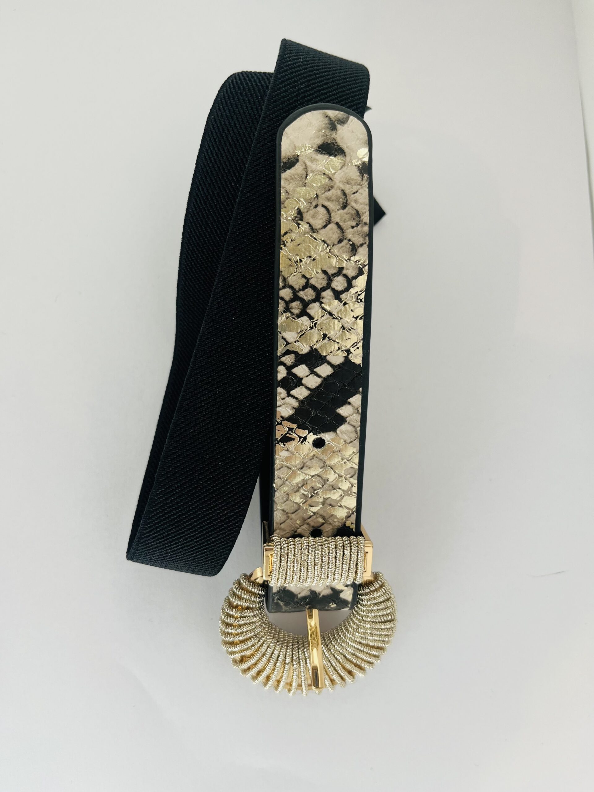 damesriem strech snake print Deze trendy damesriem is een ware blikvanger dankzij de stylishe slangenprint op de voorkant. De riem is uitgerust met een prachtige shiny gesp die een elegante combinatie van goud en zilveren metaaldraad biedt, wat zorgt voor een luxueuze uitstraling. De elastische zwarte band past zich perfect aan en geeft een flatterende uitstraling, vooral in combinatie met een zwarte broek. Hierdoor wordt de aandacht prachtig naar de gesp geleid, wat een chique detail toevoegt aan elke outfit. **Kenmerken:** - *Design:* Slangenprint op de voorkant - *Gesp:* Shiny, met een combinatie van goud en zilveren metaaldraad - *Materiaal:* Elastische zwarte band - *Stijl:* Geschikt voor casual en chique outfits Met deze riem voeg je moeiteloos een statement toe aan je look!