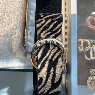 damesriem strech tijger print grijs Deze trendy damesriem is een ware blikvanger dankzij de stylish tijgerprint op de voorkant. De riem is uitgerust met een prachtige shiny gesp die een elegante combinatie van goud, wat zorgt voor een luxueuze uitstraling. De elastische zwarte band past zich perfect aan en geeft een flatterende uitstraling, vooral in combinatie met een zwarte broek. Hierdoor wordt de aandacht prachtig naar de gesp geleid, wat een chique detail toevoegt aan elke outfit. **Kenmerken:** - *Design:* tijgerprint grijs op de voorkant - *Gesp:* Shiny, met een combinatie van goud - *Stijl:* Geschikt voor casual en chique outfits Met deze riem voeg je moeiteloos een statement toe aan je look!
