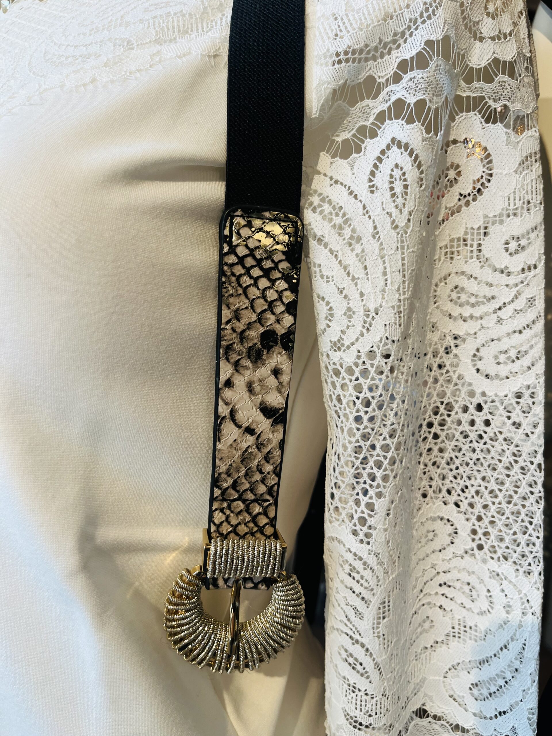 damesriem strech snake print Deze trendy damesriem is een ware blikvanger dankzij de stylishe slangenprint op de voorkant. De riem is uitgerust met een prachtige shiny gesp die een elegante combinatie van goud en zilveren metaaldraad biedt, wat zorgt voor een luxueuze uitstraling. De elastische zwarte band past zich perfect aan en geeft een flatterende uitstraling, vooral in combinatie met een zwarte broek. Hierdoor wordt de aandacht prachtig naar de gesp geleid, wat een chique detail toevoegt aan elke outfit. **Kenmerken:** - *Design:* Slangenprint op de voorkant - *Gesp:* Shiny, met een combinatie van goud en zilveren metaaldraad - *Materiaal:* Elastische zwarte band - *Stijl:* Geschikt voor casual en chique outfits Met deze riem voeg je moeiteloos een statement toe aan je look!