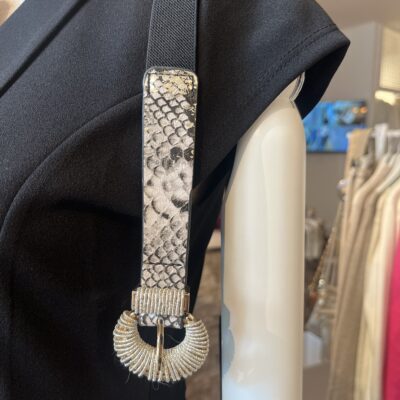 damesriem strech snake print Deze trendy damesriem is een ware blikvanger dankzij de stylishe slangenprint op de voorkant. De riem is uitgerust met een prachtige shiny gesp die een elegante combinatie van goud en zilveren metaaldraad biedt, wat zorgt voor een luxueuze uitstraling. De elastische zwarte band past zich perfect aan en geeft een flatterende uitstraling, vooral in combinatie met een zwarte broek. Hierdoor wordt de aandacht prachtig naar de gesp geleid, wat een chique detail toevoegt aan elke outfit. **Kenmerken:** - *Design:* Slangenprint op de voorkant - *Gesp:* Shiny, met een combinatie van goud en zilveren metaaldraad - *Materiaal:* Elastische zwarte band - *Stijl:* Geschikt voor casual en chique outfits Met deze riem voeg je moeiteloos een statement toe aan je look!