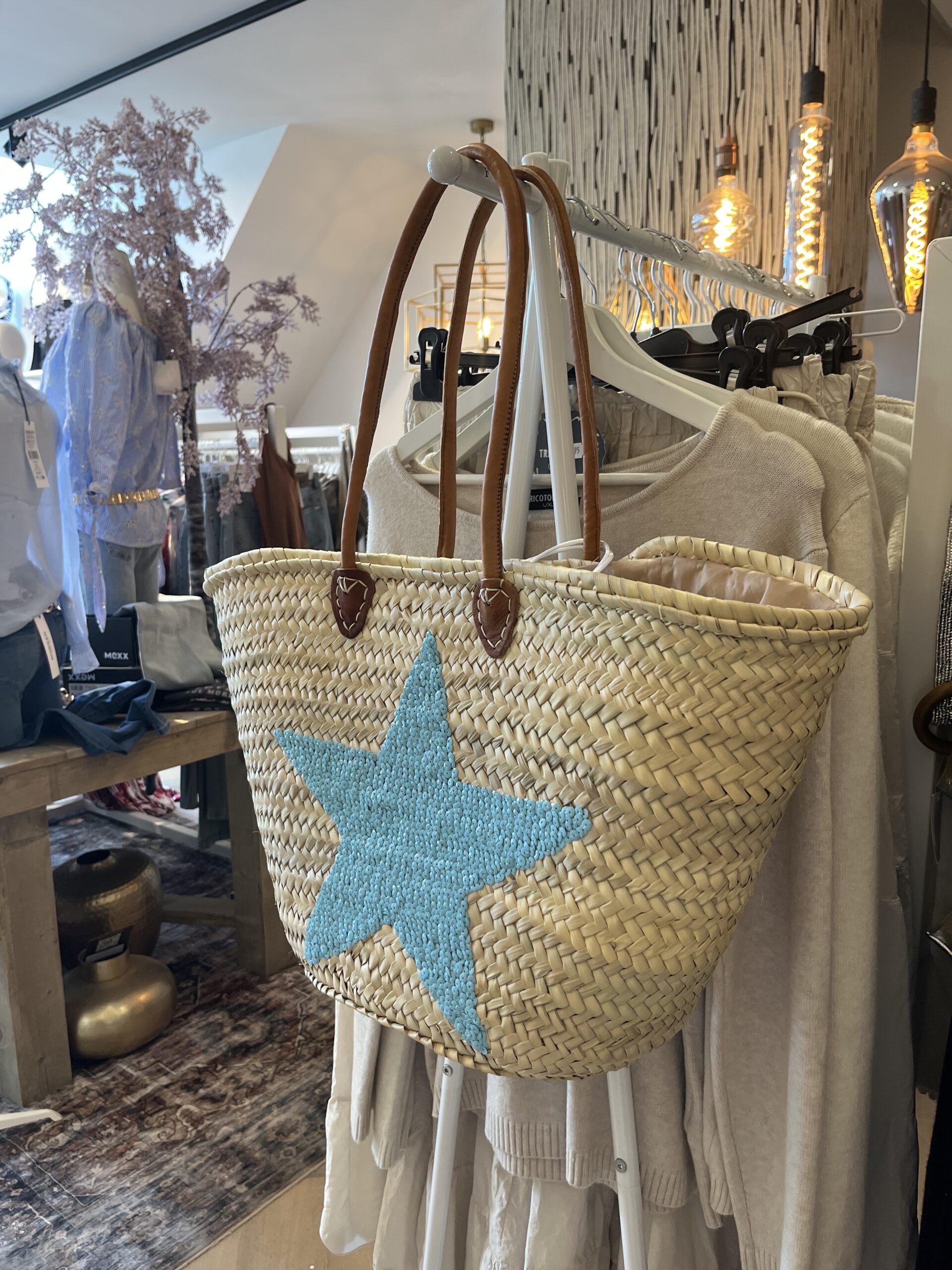 rieten strandtas ster blauw 29.95 Super gave rieten strandtas met dichte rietrand en blauwe pailletten ster Onze Westmoodz collectie rieten strandtassen zijn handmade gevlochten tassen… de pailletten zijn er stuk voor stuk opgenaaid waardoor ze stevig vast zitten op het riet. De rieten strandtas is afgewerkt met extra lange leren hengsels, zodat deze makkelijk op de schouders kan worden gedragen. De hengsels zitten vast aan de tas met metalen spikes, waardoor het geen probleem is om lekker veel spullen/gewicht mee te nemen. Dat maakt de tas heel handig en leuk als shopper…maar helemaal geweldig voor een dagje on the beach! De strandtas heeft een afsluitbare binnenvoering met tunnelkoord. Onze rieten strandtassen worden hand gemaakt in Marrakech.